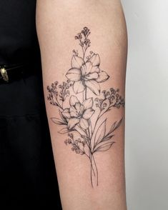 a black and white flower tattoo on the right arm, with small flowers around it