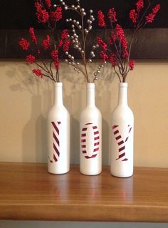 three white vases with red flowers in them