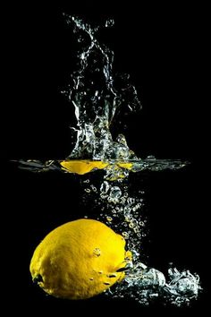 two lemons are splashing into the water