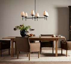 a dining room table with chairs and a vase on top of it in front of a fireplace