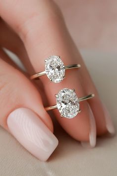 a woman's hand with two rings on her fingers and one ring in the shape of an oval diamond