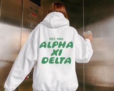 a woman wearing a white sweatshirt with the words alpha xi delta printed on it