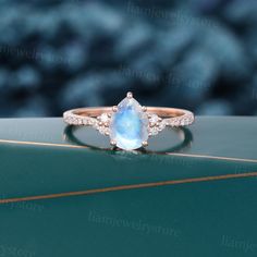 a ring with a pear shaped blue topazte surrounded by small diamonds on a green surface