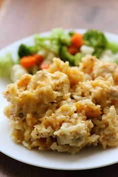 a white plate topped with food next to broccoli and carrots on a table