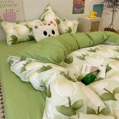 a bed with green and white sheets, pillows and a stuffed animal on the pillow