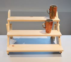 three wooden shelves with two cups on them