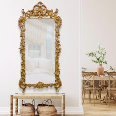 an ornate gold framed mirror sitting on top of a wooden table next to a white couch