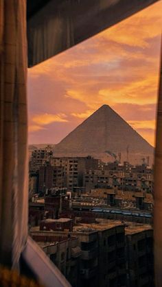 the view from inside a window looking at an egyptian city with a pyramid in the distance