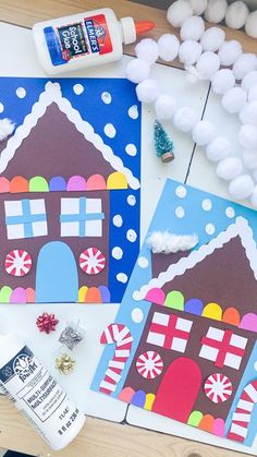 paper houses are displayed on a table with glue and other crafting supplies next to them