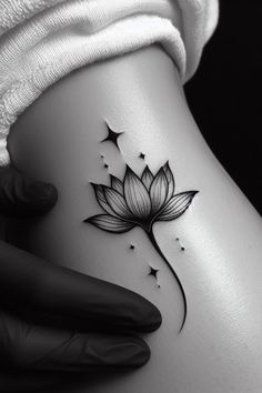 a woman's stomach with a lotus tattoo on her left side and stars in the background