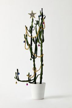 a small cactus in a white pot with beads on it's branches and a star hanging from the top