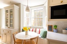 a kitchen with a table, chairs and a television mounted on the wall above it