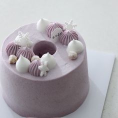 a purple cake with white frosting and seashells on top, sitting on a piece of paper