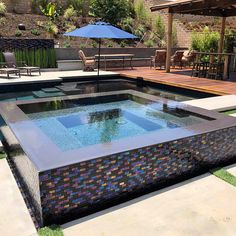 an outdoor swimming pool surrounded by patio furniture and umbrellas in the back yard area