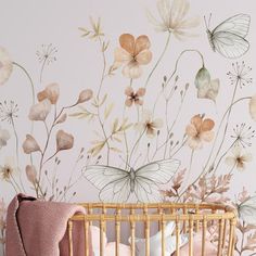 a baby's crib in front of a wall with flowers painted on it