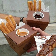 two people are holding up boxes with food in them and dipping sauce on the side