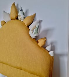 a bed with yellow sheets and pillows on it's headboard, against a white wall