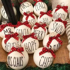 a pile of white christmas balls with words on them sitting next to some black and white striped stockings