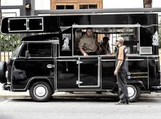 a man standing next to a black food truck