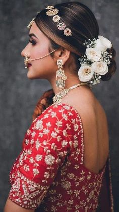 a woman in a red and gold dress with flowers in her hair, looking off to the side