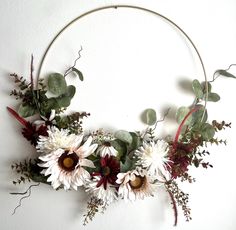 a wreath with flowers and greenery hanging on the wall