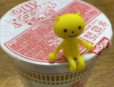 a small yellow toy sitting on top of a cup