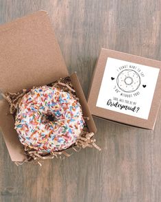 a donut with sprinkles sits in a box next to a card