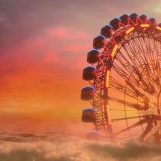 a ferris wheel in the clouds at sunset