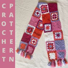 a crocheted scarf is laying on a white blanket with pink and red trim