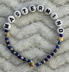 a beaded bracelet with the word master and star on it, sitting on top of a white blanket