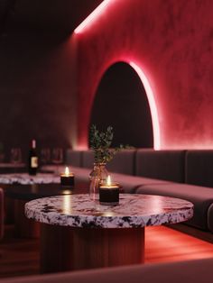 a table with candles and a vase on it in a room that has red lighting