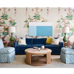 a living room filled with blue couches and colorful wallpaper on the walls behind them