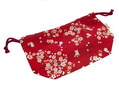 a red bag with white flowers and birds on it, sitting on a white surface