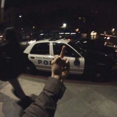 a police car parked on the side of a road next to a person holding up a cell phone