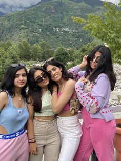 four girls are posing for the camera with mountains in the background