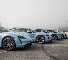 three blue sports cars parked in a parking lot next to each other on a foggy day