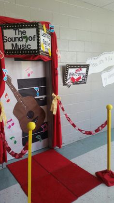 a red carpeted hallway with a door decorated like a musical instrument and some yellow poles