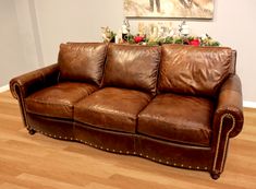 a brown leather couch sitting on top of a hard wood floor