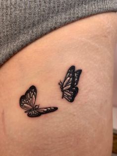 two butterflies tattoo on the side of a woman's thigh, one is black and white