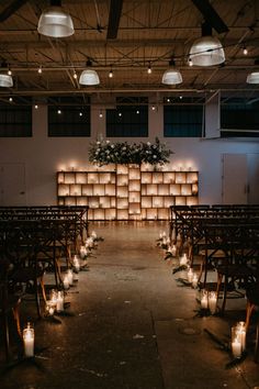 an empty church with rows of chairs and lit candles in front of the back wall