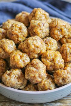 a white bowl filled with meatballs on top of a wooden table next to a blue towel