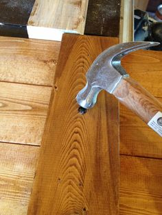 an old hammer is sitting on top of a piece of wood