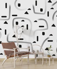 a chair and table in front of a wall with black and white designs on it