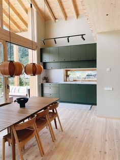 a dining room and kitchen area with wood flooring, green cabinets and wooden ceiling lights