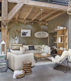 a living room filled with lots of furniture next to a tall wooden beamed ceiling