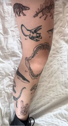 a person with tattoos on their legs is standing in front of a white sheet that has dinosaurs