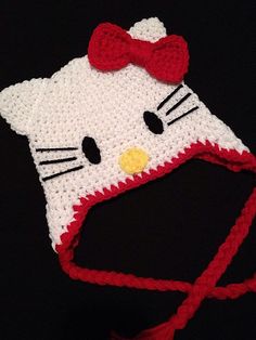 a crocheted hello kitty hat with a red bow