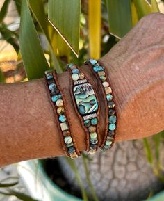 This 3-wrap bracelet that can also be worn as a hat band is hand made with natural turquoise, abalone, and picture jasper with an abalone focal in the center  The stones and focal are bound on natural light brown distressed leather.  It measures approximately 19.5" to 29" with a silver button and 8 loop button holes for closure.  It has a flexible fit so it can either be worn around the average wrist 3 times as a bracelet or worn once around a hat as a hat band.   This wrap will be packaged in a Artisan Turquoise Hand Wrapped Wrap Bracelet, Artisan Hand Wrapped Turquoise Wrap Bracelet, Hand Wrapped Turquoise Spiritual Wrap Bracelet, Adjustable Natural Stone Wrap Bracelet For Festivals, Handmade Turquoise Wrap Bracelet, Adjustable Natural Stones Wrap Bracelet, Adjustable Turquoise Bohemian Wrap Bracelet, Adjustable Bohemian Turquoise Wrap Bracelet, Rustic Adjustable Hand-wrapped Bracelet