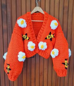 an orange sweater with flowers and bees on it