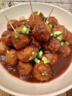 a white plate topped with meatballs covered in gravy and toothpicks